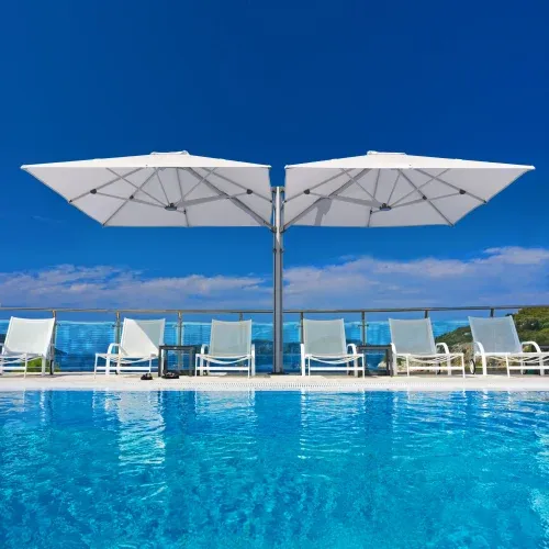 Dual cantilever umbrella with white canopies next to a swimming pool